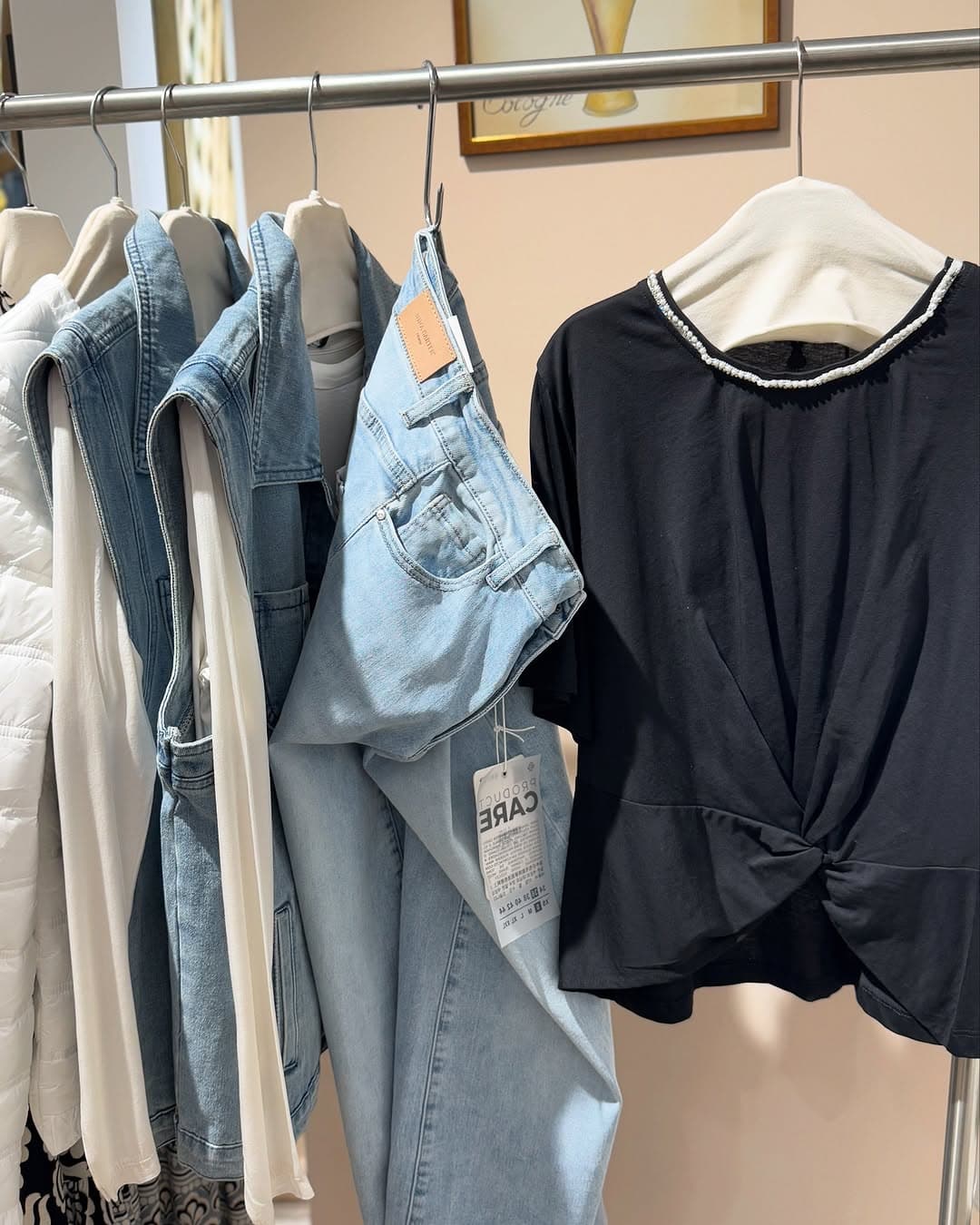 Collezione di jeans denim e capi casual appesi su stender