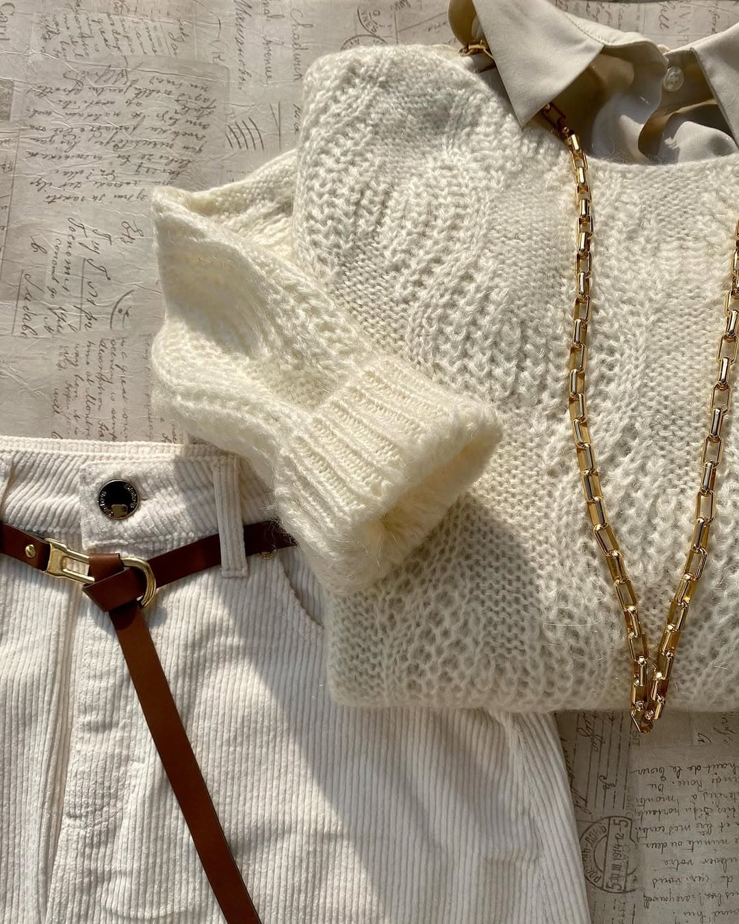 Outfit coordinato total white con maglione in maglia e dettagli oro