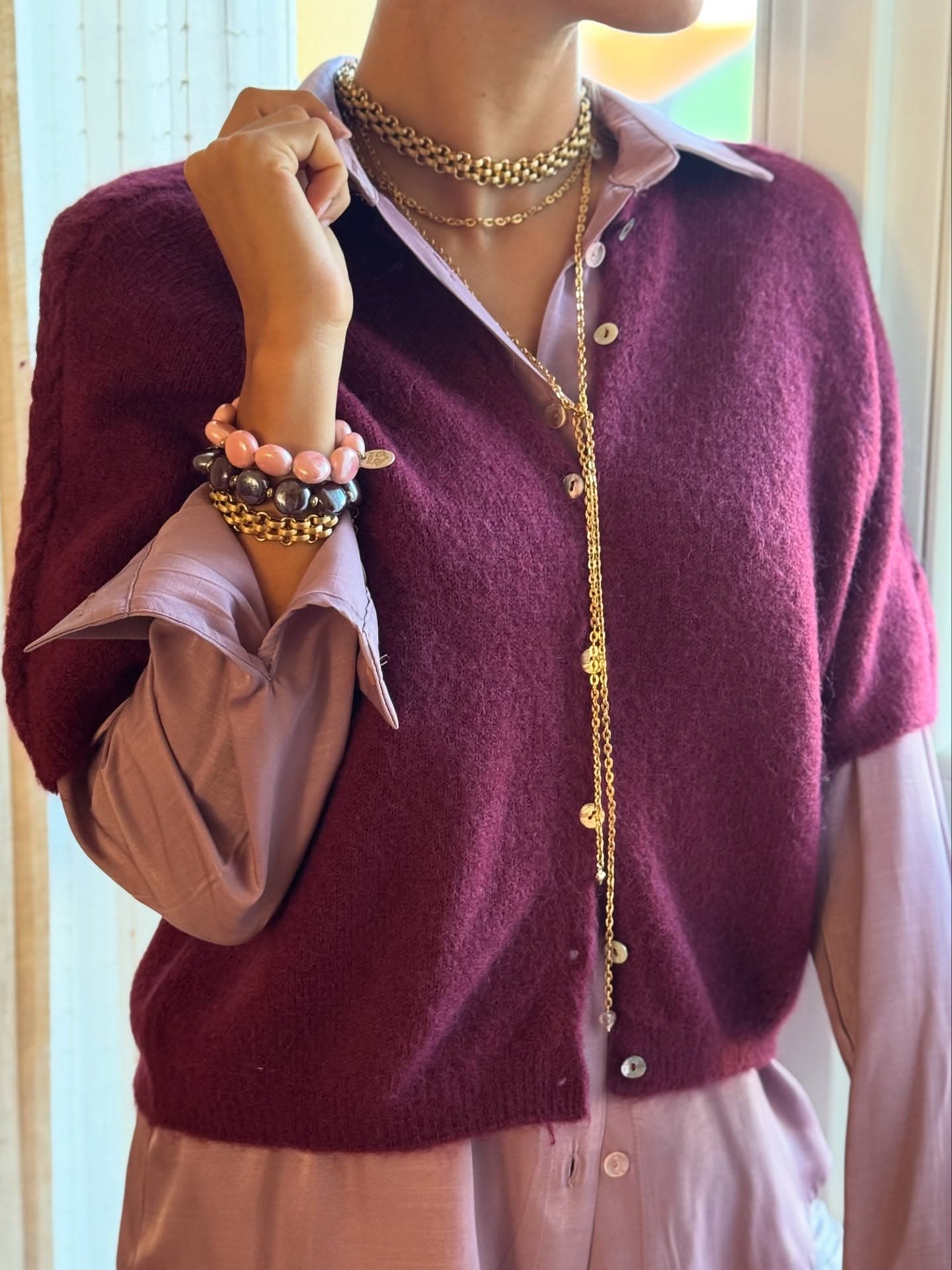 Look completo con cardigan bordeaux, camicia rosa e gioielli dorati stratificati