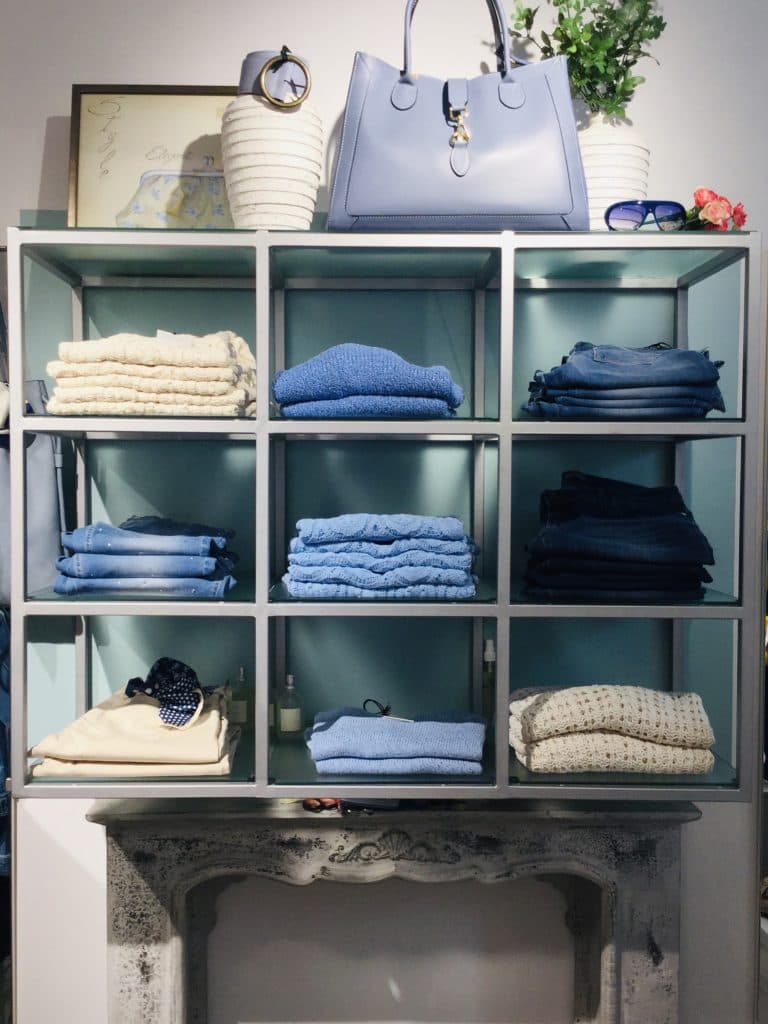 Esposizione negozio con maglioni e jeans ordinati in cubetti turchesi